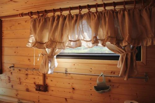 a window with curtains hanging in a room at V dedine a predsa mimo nej v maringotke na samote in Dechtice