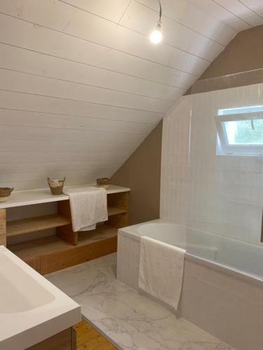 une salle de bain blanche avec une baignoire et un lavabo dans l'établissement MAISON STERNA : maison familiale en bord de mer, à Kerouguel