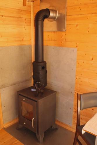 a stove in a room with a wooden wall at V dedine a predsa mimo nej v maringotke na samote in Dechtice