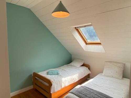 une chambre avec deux lits dans un grenier dans l'établissement MAISON STERNA : maison familiale en bord de mer, à Kerouguel