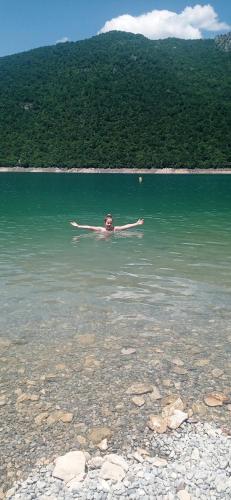 a person laying on a kayak in a body of water at Apartment HOLIDAY LAKE - PIVA 2022 in Pluzine