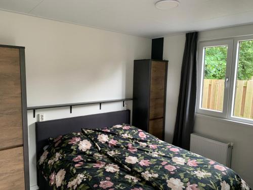 a bedroom with a bed with a floral bedspread at Chalet Moderna Putten in Putten