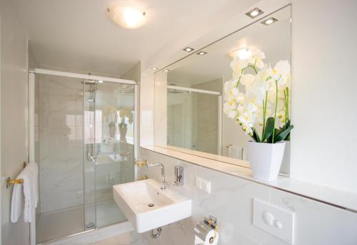 La salle de bains est pourvue d'un lavabo et d'une douche avec un miroir. dans l'établissement Gästehaus am Herrendeich, à Nordstrand
