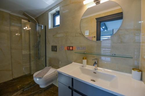 uma casa de banho com um lavatório, um WC e um espelho. em SEA ESTA VILLA 4 em Fethiye