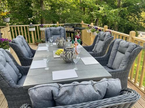 a table with wicker chairs and a table with wine glasses at MOEL SIABOD - GLAN GWNA HOLIDAY PARK in Caernarfon