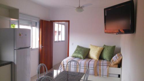 Una sala de estar con un sofá y un televisor en la pared. en Apartment Residencial Lídia Milani, en Florianópolis