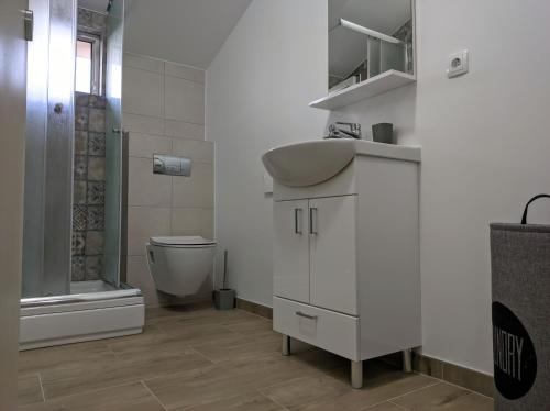 a white bathroom with a sink and a toilet at Villa Longina in Ljubuški