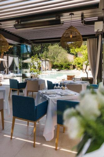 a restaurant with white tables and chairs and ailion with at MUSE Saint Tropez - Small Luxury Hotels of the World in Saint-Tropez