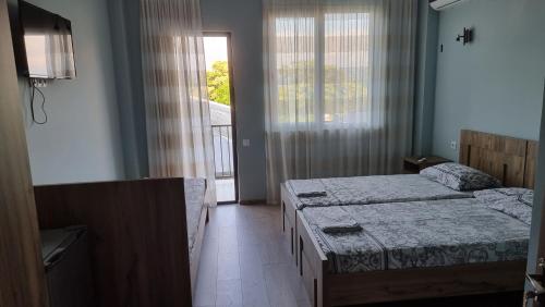 a bedroom with two beds and a window and a television at French Hotel in K'obulet'i