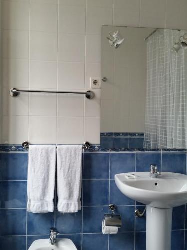 a blue and white bathroom with a sink and a mirror at Pensao Lourenco in Curia