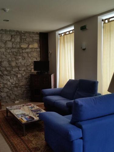 a living room with blue couches and a coffee table at Pensao Lourenco in Curia