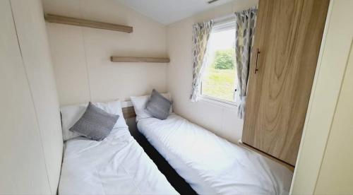 two beds in a small room with a window at Tunstall view Caravan Holidays at Sand le Mere in Tunstall