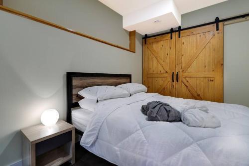 a bedroom with a white bed with a wooden door at Adorable private suite with indoor fire place in Cochrane
