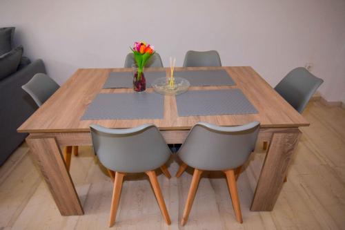 a wooden table with chairs and a vase of flowers on it at Eclectic Apartment with Stunning Seaview in Porto Rafti
