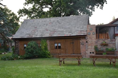a building with two benches in front of it at Gosciniec Pod Debem in Trzciel
