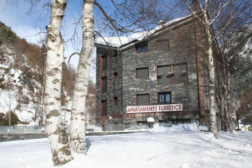 a building with a sign on it in the snow at Apartaments Turístics Prat de Les Mines in Ordino
