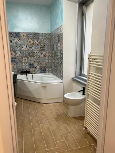 a bathroom with a tub and a toilet at Alla Scalinata del Teatro Rossetti confort suites parcheggio in Trieste