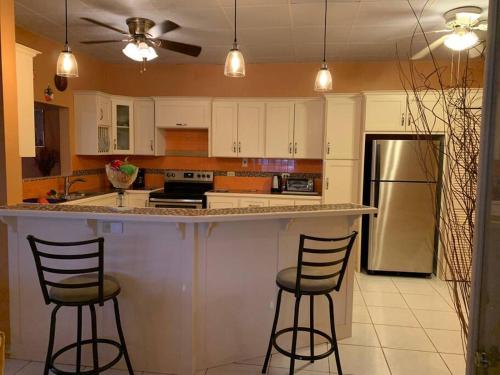 a kitchen with two bar stools and a refrigerator at Vista Stays ...Alluring Ambrosia near to Airport in Trincity 