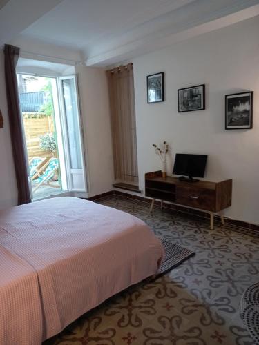 um quarto com uma cama e uma secretária com uma televisão em Côté cour em Lorgues