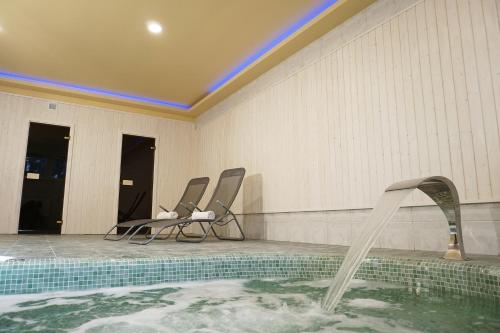 a swimming pool with two chairs and a hot tub at Anna Panzió & Wellness Siófok in Siófok