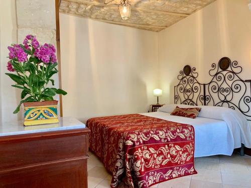 a bedroom with a bed and a vase with purple flowers at Scicli Albergo Diffuso in Scicli