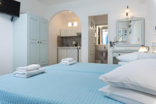 two beds in a white room with towels on them at Castello studios in Agia Anna Naxos