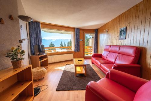 a living room with a red couch and a window at Eden Resort Anzère in Anzère