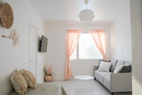 a white living room with a couch and a window at West Coast Hideaway in Pietarsaari