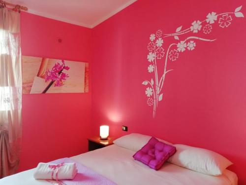 1 dormitorio con paredes rosas y 1 cama con almohadas moradas en Prendas Antigas - vacanze a Teulada, en Teulada