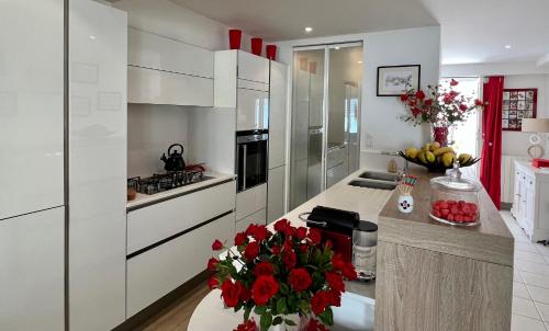 een keuken met witte kasten en rode bloemen op een aanrecht bij 120m2 avec deux terrasses ensoleillées à Biarritz in Biarritz