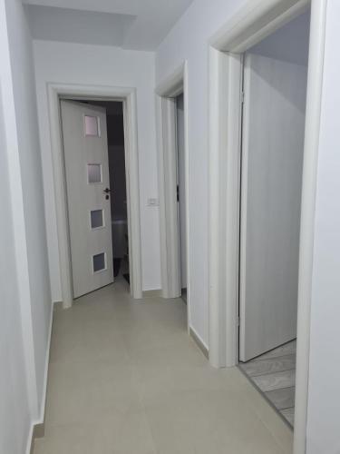 un pasillo vacío con paredes blancas y espejo en Deluxe 2 bedroom apartment with balcony and private parking, en Bragadiru