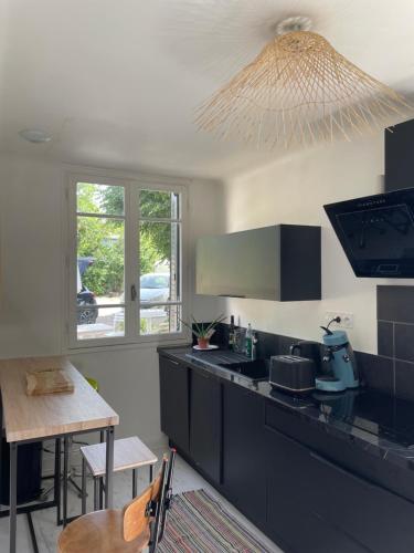 eine Küche mit schwarzen Arbeitsflächen, einem Tisch und einem Fenster in der Unterkunft La maison de Badet in Bozouls