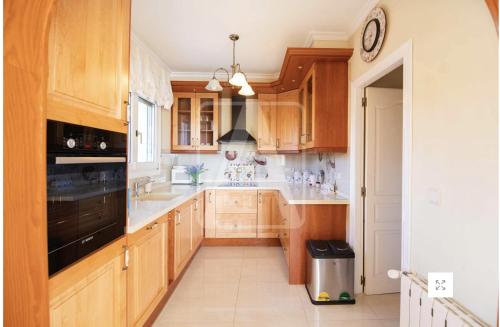 a kitchen with wooden cabinets and a black appliance at Casa Sofia in Calpe