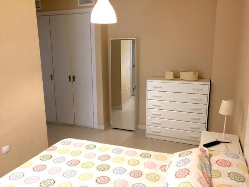 een slaapkamer met een bed, een dressoir en een spiegel bij Tarifa Apartamento piscina ideal familia niños in Tarifa