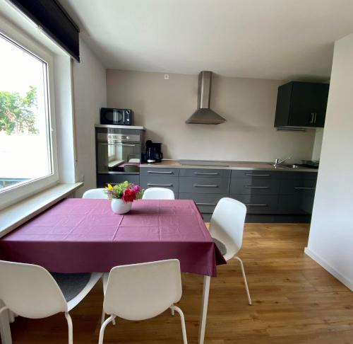 メミンゲンにあるAllgäulodge Memmingenのキッチン(紫色のテーブル、白い椅子付)