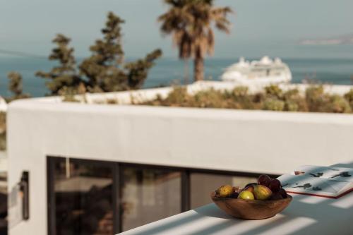 a bowl of fruit on a table with a cruise ship in the background at Asty Mykonos Hotel & Spa - World of One Hotel Group in Mýkonos City