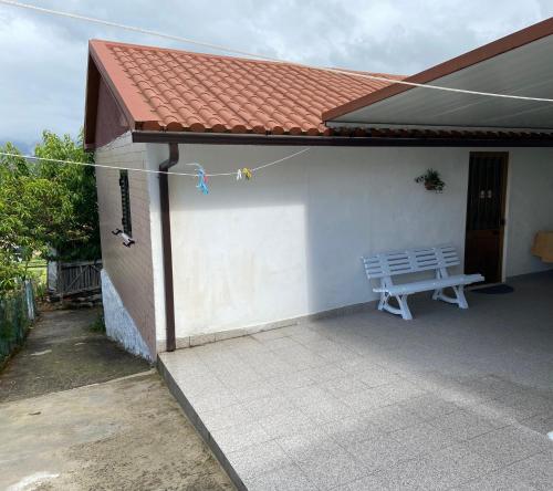 una casa blanca con un banco y una mesa en Alojamento da Ribeirinha, en Cárquere