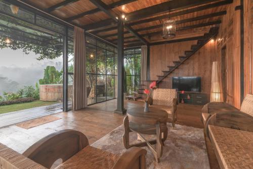 a living room with wooden walls and a large window at Kayukopi in Munduk