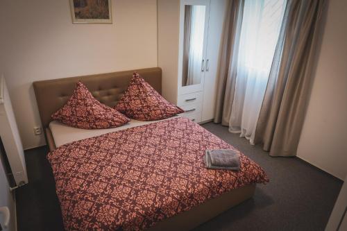 a bedroom with a bed with red comforter and pillows at Hotel Apartment Faraon in Rumburk
