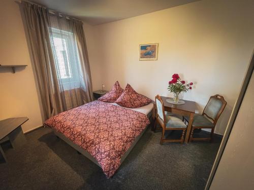 a bedroom with a bed and a table with a vase of flowers at Hotel Apartment Faraon in Rumburk