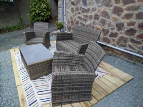 drie rieten stoelen en een tafel op een patio bij Appartement entier, vue sur rivière & cathédrale. in Plouguiel