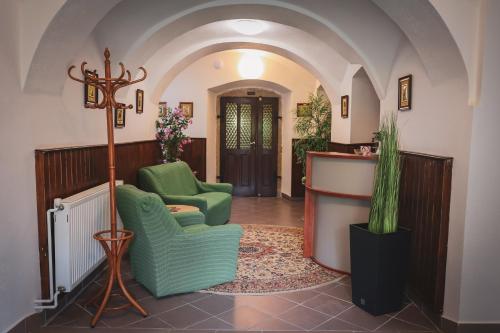 a lobby with two green chairs and a bar at Hotel Apartment Faraon in Rumburk