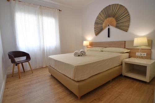 a bedroom with a bed and a chair and a mirror at Apartament galan1966 in L'Escala