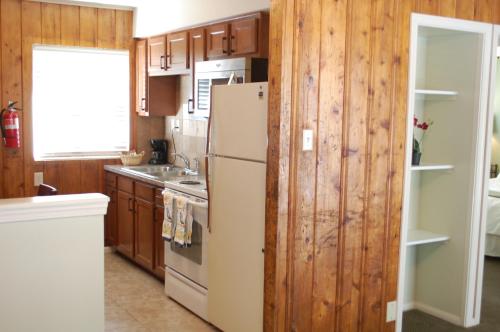 a kitchen with a white refrigerator and wooden cabinets at El Rancho Motel in Bishop