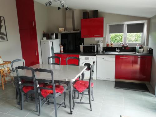 une cuisine avec des armoires rouges et une table et des chaises dans l'établissement au coeur des coteaux du Layon, à Le Champ-sur-Layon