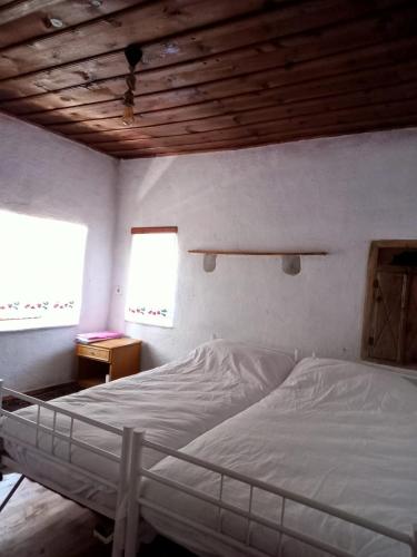 a bedroom with a white bed and two windows at Koca Kapı Konaklama in Yeşilova