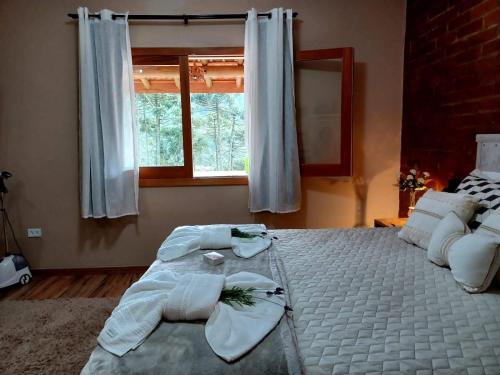 a bedroom with a large white bed with towels on it at Sopro da Serra Chalés in Gonçalves