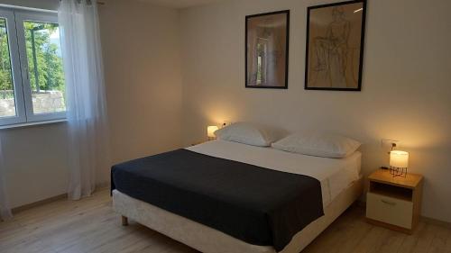 a bedroom with a bed with two lamps and two pictures on the wall at Apartments Močići in Močići