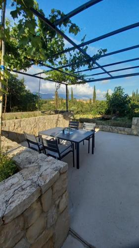 a patio with a table and chairs and a stone wall at Apartments Močići in Močići