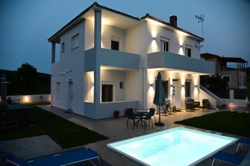 a white house with a swimming pool in front of it at BIG BLUE HOTEL in Amaliápoli